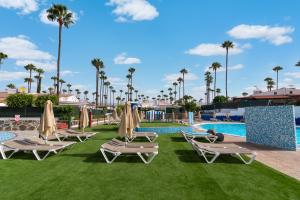 a pool with lounge chairs and umbrellas at a resort at Dreams Home in Maspalomas