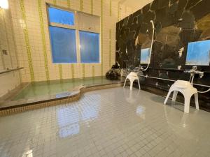 ein Badezimmer mit einer Badewanne und zwei weißen Stühlen in der Unterkunft ＳＥＫＫＡ ＳＨＩＲＥＴＯＫＯ - Vacation STAY 66952v in Shimatokkari