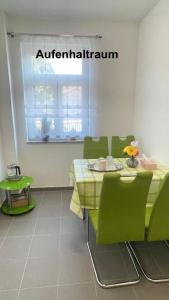 a dining room with a table and green chairs at Kim Homestay A Zimmer 1 in Sömmerda