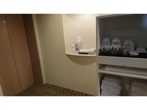 a small bathroom with a shelf with bottles of water at Smile Hotel Nagoya Shinkansenguchi - Vacation STAY 77718v in Nagoya +25 photos