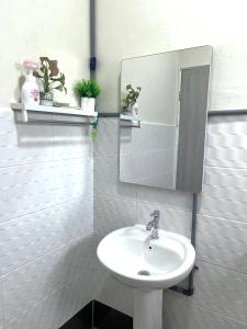 a white bathroom with a sink and a mirror at The Hydrangea House in Kota Kinabalu