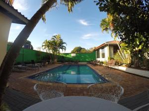 a swimming pool with chairs and a house at POUSADA EVELINA in Foz do Iguaçu