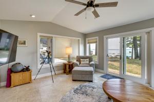 a living room with a ceiling fan and a chair at Swim, Fish and Boat House on Stunning Higgins Lake! in Higgins Lake