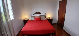 a bedroom with a red bed with two lights on the sides at Três Marias - Shared Countryside Connection in Lanceiros