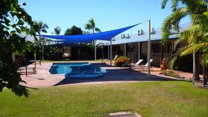 a swimming pool with a blue canopy in a yard at Lakeview Apartments in Kununurra