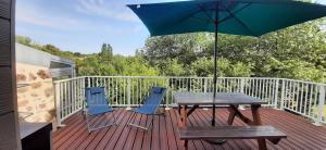 a wooden deck with a table and chairs and an umbrella at La Péra in Putanges