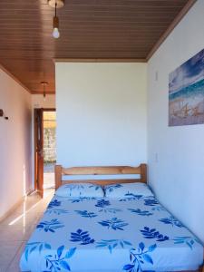 a bed in a room with a blue comforter at Mar Doce Lar Suítes Trindade in Trindade