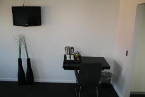 a black table with a chair and a tv on a wall at Seaside Hotel Thyborøn in Thyborøn