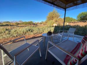 a patio with chairs and a table with a view of a field at Cielo Tiny House in San Pedro de Atacama