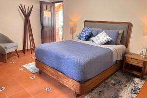 a bedroom with a bed with blue sheets and a chair at Refugio familiar en el bosque in Villa Victoria +23 photos