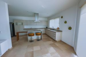 a kitchen with a sink and two bar stools at Villa Cerca de Punta de Mita 90 in Cruz de Huanacaxtle