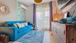 a living room with a blue couch and a window at PARADISIAC LAGOON in Saint-François