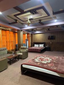 a hotel room with two beds and chairs at Saman Hotel in Gilgit
