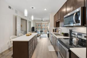 a kitchen with wooden cabinets and a large kitchen island at Chill & Tone 1BR Frisco King & Sofa, Gym & Pool in Frisco