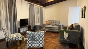 a living room with a couch and chairs and a tv at Casa Los Yoses 47 in San Pedro