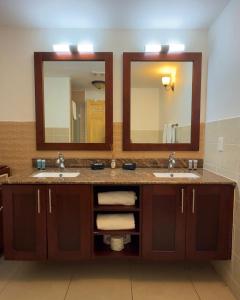 a bathroom with two sinks and two mirrors at Maho Beach Beautiful Garden Studio in Maho Reef