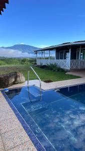 a swimming pool with a metal handrail in front of a house at Quinta La Lomita in Turrialba