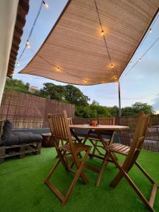 a wooden table and two chairs under an umbrella at Azorean Stays T1 in Lomba da Cruz