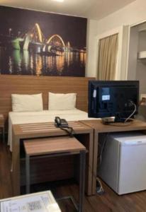 a room with a bed and a desk with a television at S4 HOTEL AGUAS CLARAS TorresReis2 in Brasilia