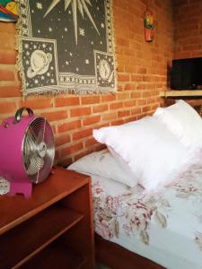 a bedroom with a bed and a table with a fan at Winará - Turismo de aventura in São Thomé das Letras
