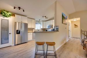 a kitchen with white cabinets and a bar with stools at Comforting Woodland Park Home with Fire Pit! in Woodland Park