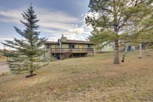 a house on a hill with trees in front of it at Comforting Woodland Park Home with Fire Pit! in Woodland Park