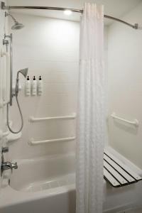 a white shower curtain in a bathroom with a tub at SpringHill Suites by Marriott Lake Charles in Lake Charles