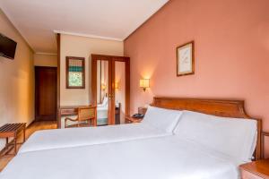 ein Schlafzimmer mit einem großen weißen Bett und einem Schreibtisch in der Unterkunft B&B HOTEL Gijón Centro Begoña in Gijón + 9 Fotos