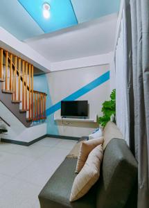 a living room with a couch and a tv at Host Homes - Gomez St 1 or 2BR Apartelle in Tacloban