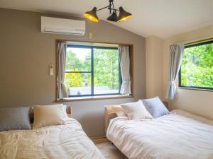 a bedroom with two beds and a window at Harmonia 那須,大人数,カラオケ,屋根付きBBQ,敷地内の小川 in Nasu
