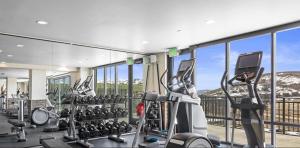 ein Fitnessstudio mit vielen Trainingsgeräten und Fenstern in der Unterkunft Luxury Black Rock Resort Suite Unit A in Heber City