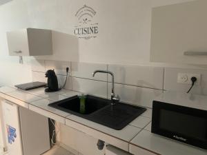a kitchen counter with a sink with a faucet at Elkana in Montjoly