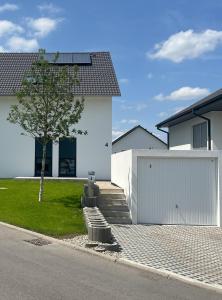 ein weißes Haus mit einer Garage und einem Baum in der Unterkunft Ferienzimmer No4 Ehingen in Ehingen