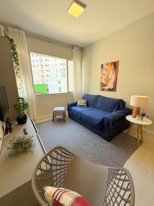 ein Wohnzimmer mit einem blauen Sofa und einem Fenster in der Unterkunft Apartamento no Centro - conforto e praticidade in Florianópolis