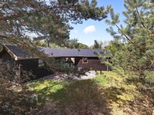 une maison avec un toit noir dans les bois dans l'établissement 8 person holiday home in Fjerritslev-By Traum, à Fjerritslev