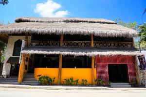 a building with a thatched roof with a yellow front at Hotel Diosa del Agua Bacalar in Bacalar