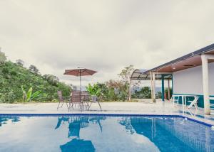 a pool with chairs and an umbrella next to a house at Rancho Buenavista in Vergara