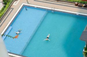 two people swimming in a large swimming pool at Monarchy Luxury Serviced Apartments - By Charm Homestay Vietnam in Danang