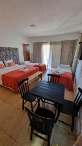 a hotel room with two beds and a table and chairs at Pousada Village Gostoso in São Miguel do Gostoso