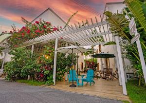a white pergola with chairs and tables and flowers at Hotel California Miyakojima Resort in Miyako Island