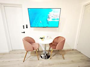 mesa con 2 sillas y TV en la pared en Luz Maria 8 MaiaHome Prime Spot in Polanco with Terrace, en Ciudad de México