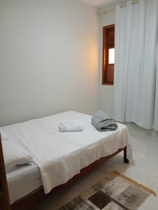 a white bedroom with a bed with towels on it at Apartamento térreo in Vitória