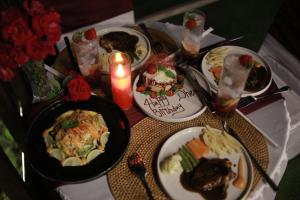 a table with plates of food and a candle at Jukung Villa Lampung in Hajimana