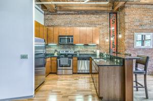 a kitchen with wooden cabinets and a brick wall at Denim Lofts-DWTN Loft Walk to Sports, Stadiums & Convention-2D in Saint Louis