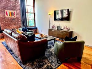 a living room with two couches and a tv at Denim Lofts-DWTN Loft Walk to Sports, Stadiums & Convention-2D in Saint Louis