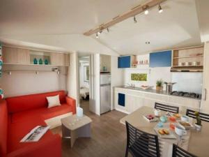滨海布朗Mobil-home spacieux avec terrasse - 3 chambres - 6 personnes - API-1-52-452的客厅里有一张红色的沙发和一张桌子