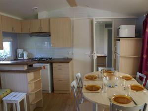 a kitchen with a table and chairs in a room at Confortable Mobil Home 6 personnes avec terrasse à Meyrueis - API-1-52-342 in Meyrueis +15 photos