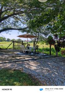 a table and chairs under an umbrella in a field at villa tempoyak homestay in Pantai Cenang