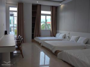a bedroom with two beds and a table and a desk at Thatico Homestay 2 in Thôn Mỹ Phước