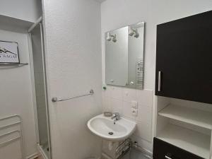 ein weißes Badezimmer mit Waschbecken und Spiegel in der Unterkunft Appartement Sud avec Terrasse et Garage à Super Besse - FR-1-814-96 in Besse-et-Saint-Anastaise + 9 Fotos